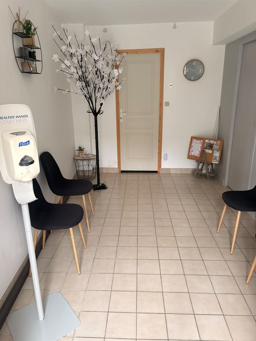 Entrée de la salle d'attente avec un distributeur de gel hydroalcoolique sur pied.