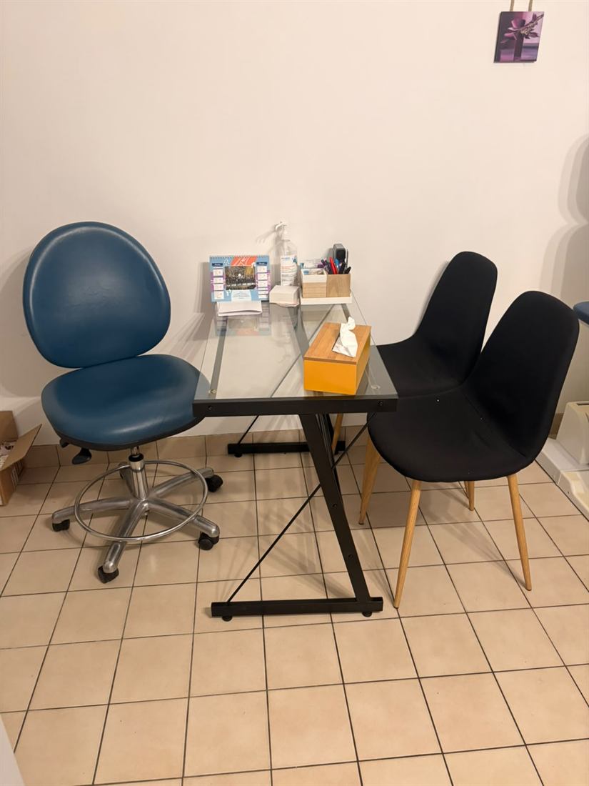 Bureau en verre du cabinet avec tabouret bleu réglable et deux chaises visiteurs.