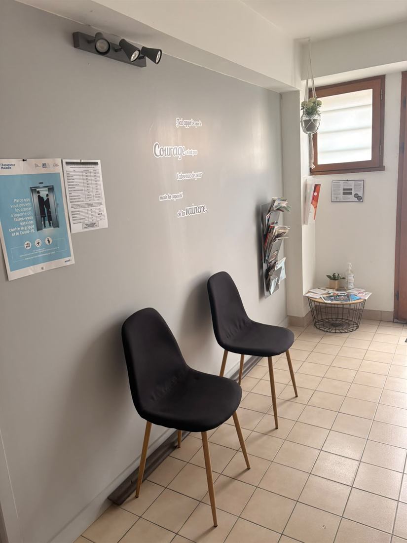 Mur de la salle d'attente portant une citation sur le courage, avec présentoir de documentation santé.