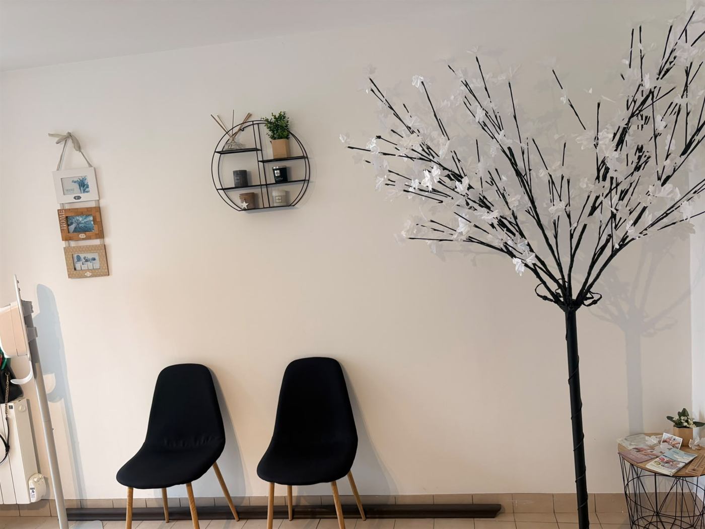 Salle d'attente du cabinet infirmier de Martigné-sur-Mayenne : murs clairs, chaises noires et arbre décoratif blanc.